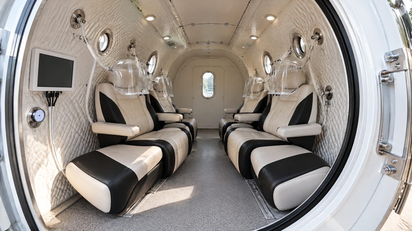 Interior of a multiplace hyperbaric chamber with two rows of seats and individual oxygen hoods